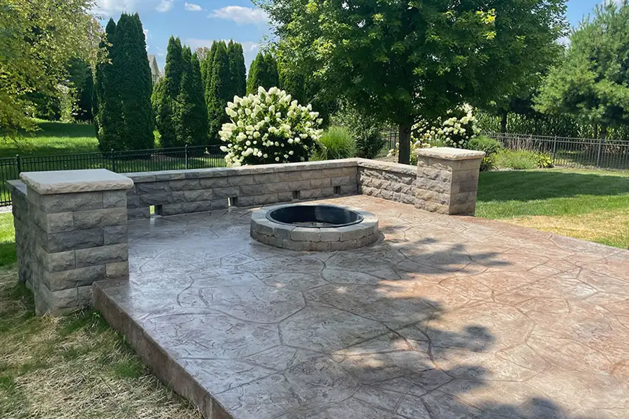 Stamped concrete patio with fire pit and rock retaining walls - Chatham, IL