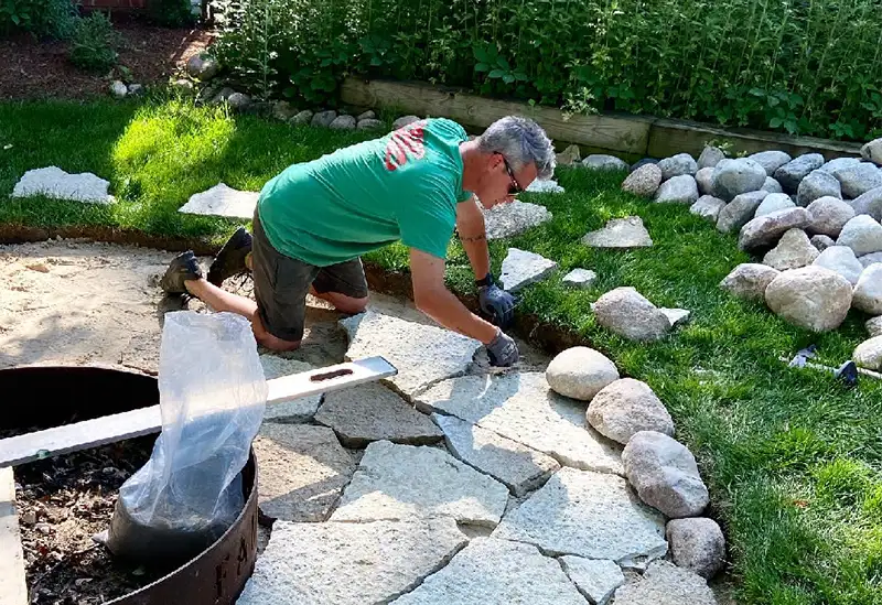 Deep Roots - worker laying out flagstone patio around new fire pit - Chatham, IL
